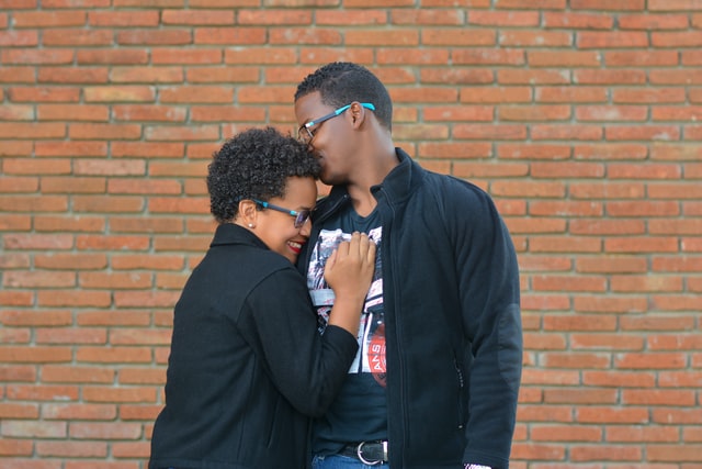 Homem negro beijando cabeça de mulher negra.