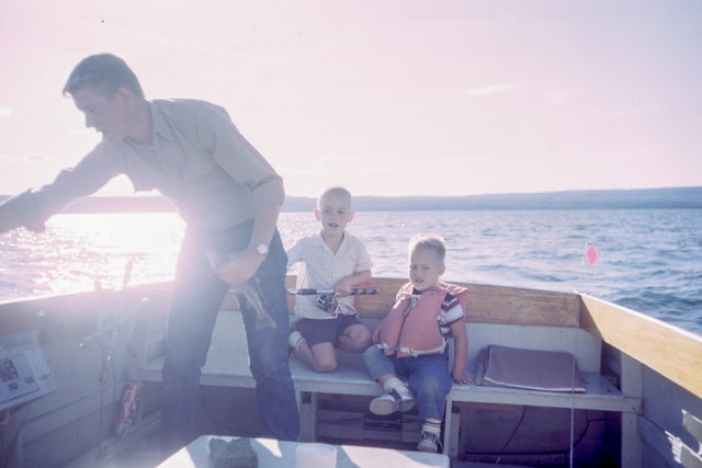 Pai e seus dois filhos em um pequeno barco sobre a água
