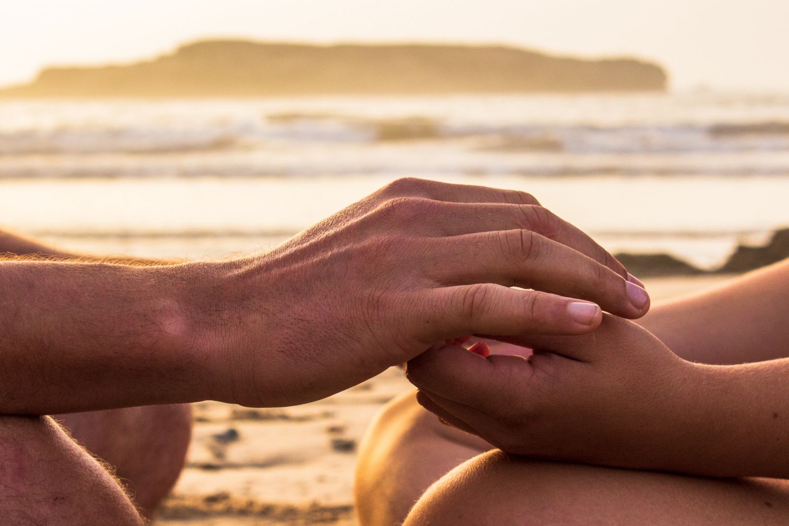 Duas pessoas com as mãos encostadas na praia