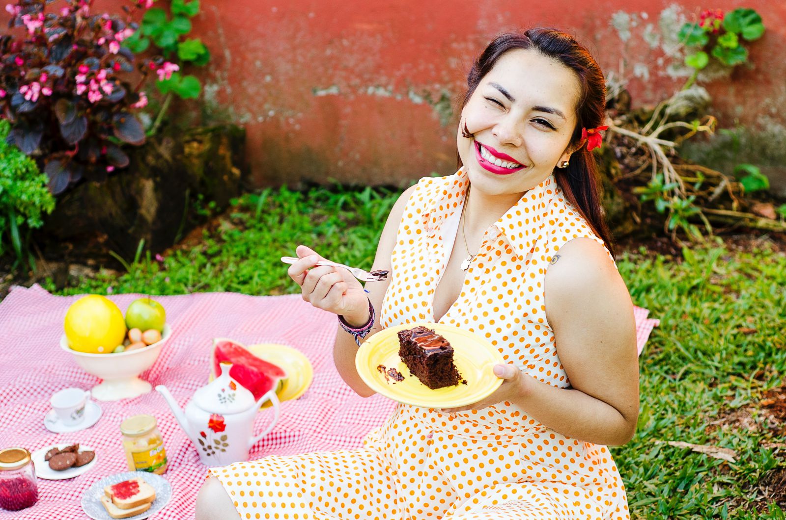 Mulher comendo um bolo de chocolate ao ar livre, em um piquenique.