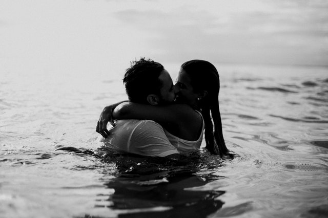 Homem e mulher se beijando na água.