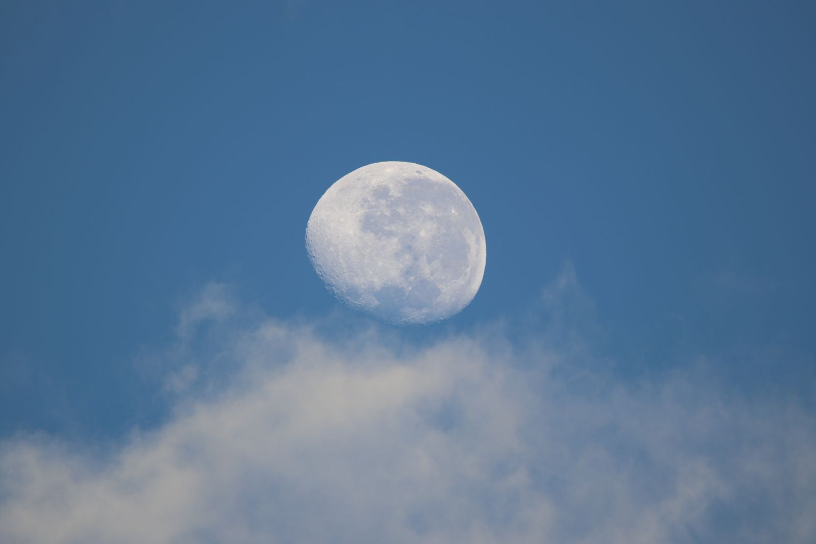 Lua cheia vista sobre nuvens em um céu limpo.
