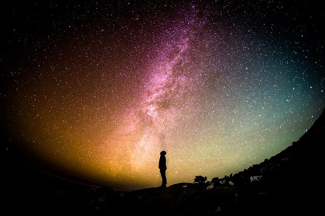 Silhueta de uma pessoa olhando para o céu estrelado.