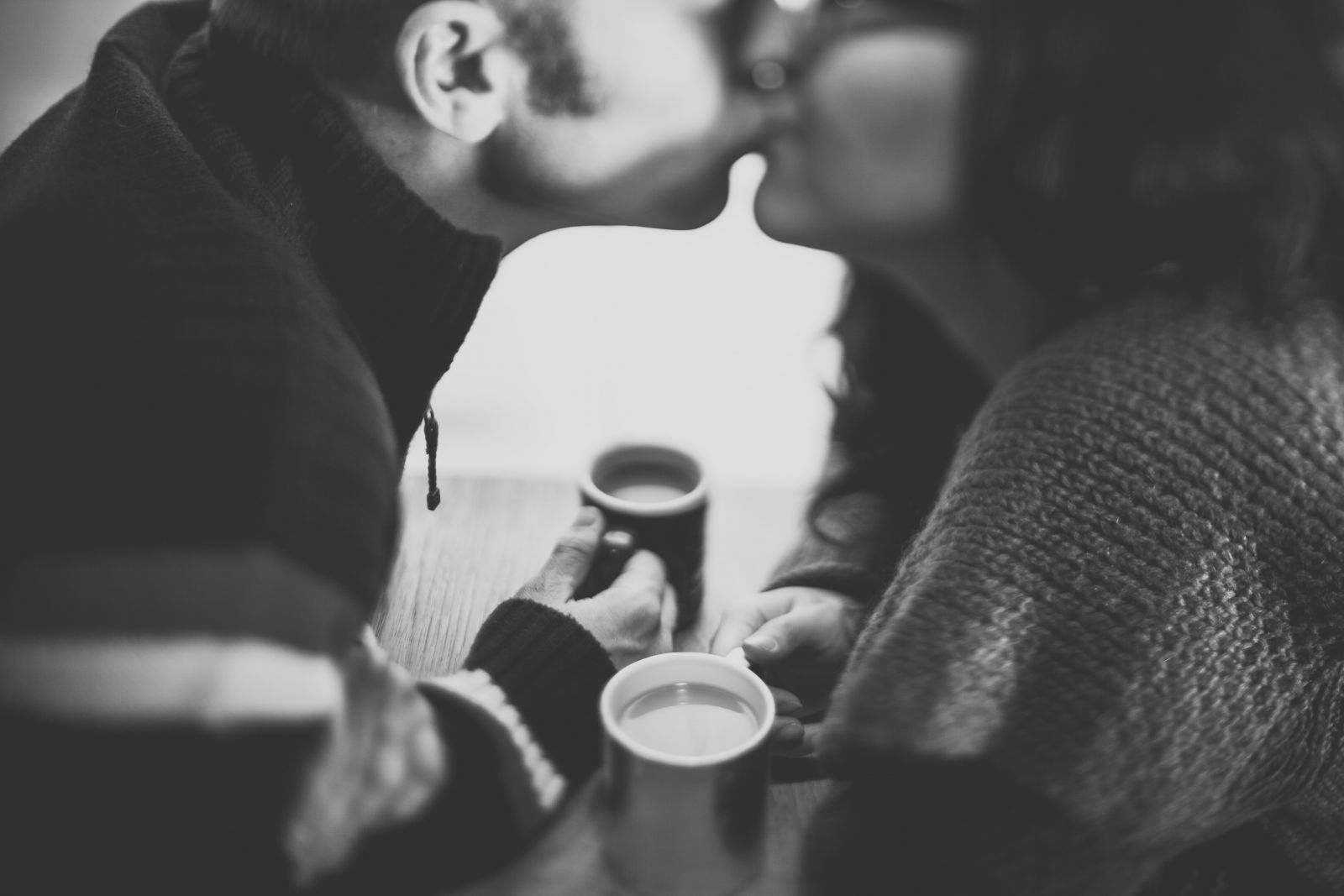 Casal se beijando segurando xícara de chá