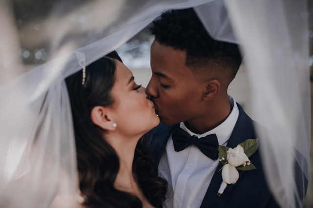 Homem negro e mulher branca se beijando.