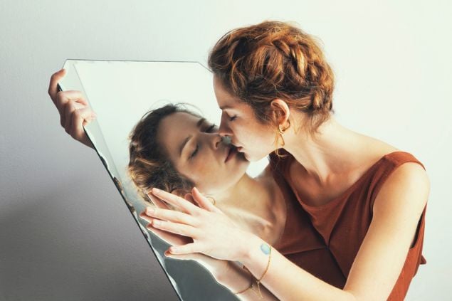 Mulher beijando o próprio reflexo no espelho.