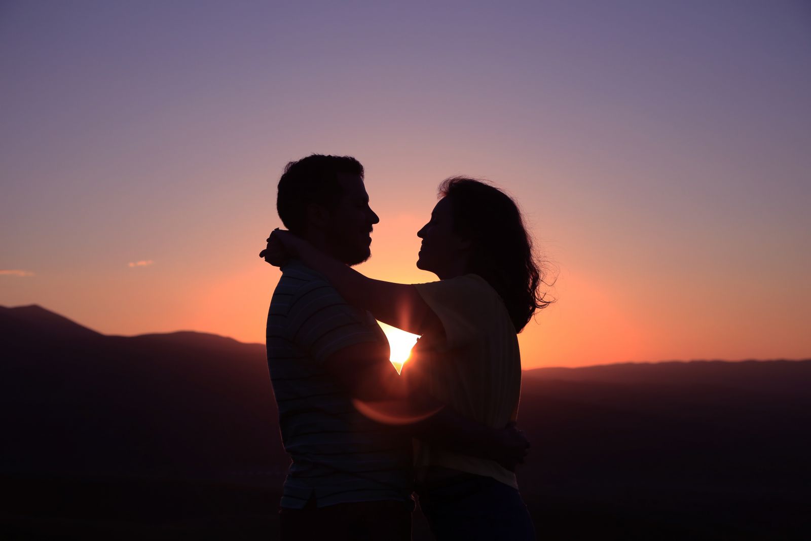 Silhueta de casal abraçados com a luz do pôr do sol