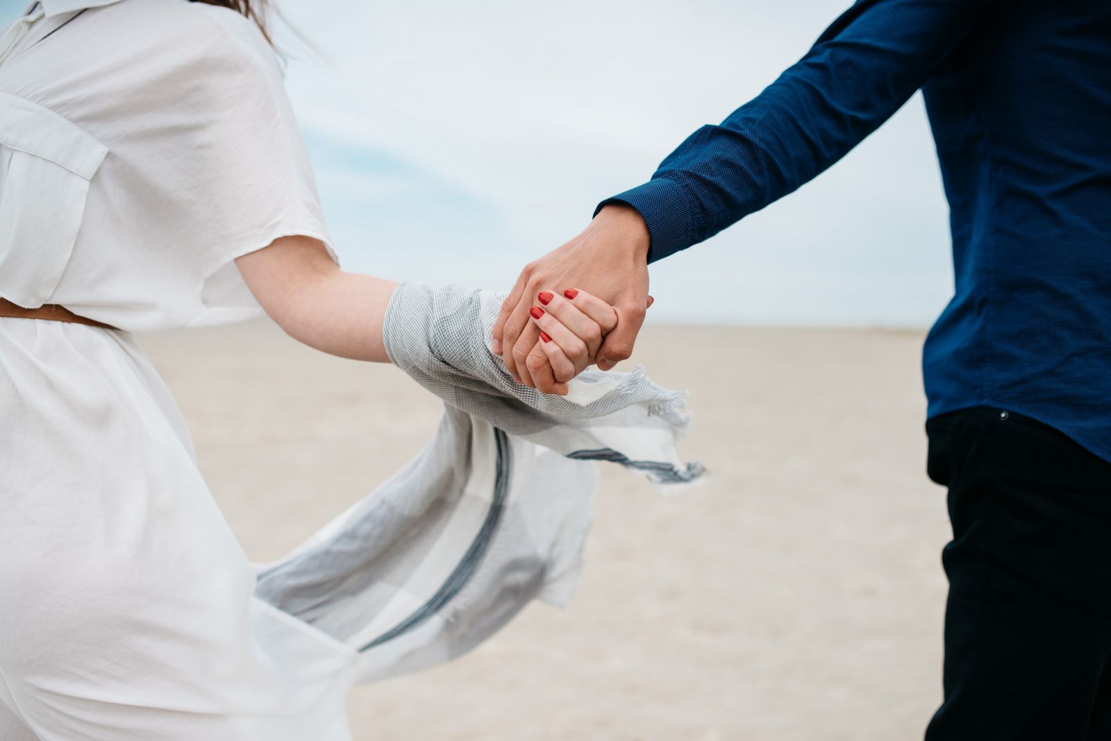 Homem e mulher correndo juntos com suas mãos dadas em uma praia