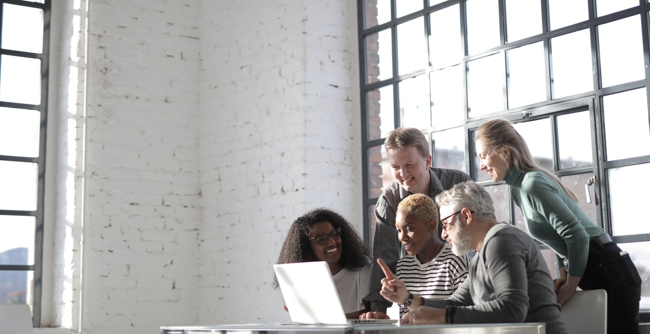Pexels/Andrea Piacquadio Mulher em frente a notebook, com várias pessoas ao redor dela, vendo algo em comum.