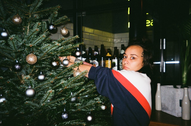 Mulher olhando com cara de brava para a câmera enquanto arruma a árvore de Natal