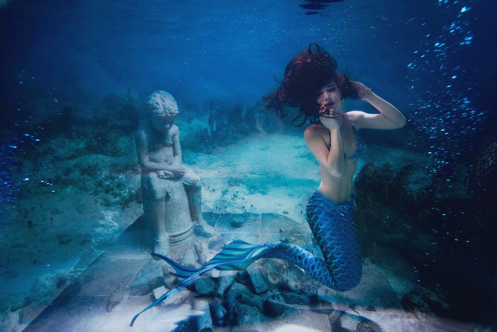 Sereia no mar ao lado de uma estátua 