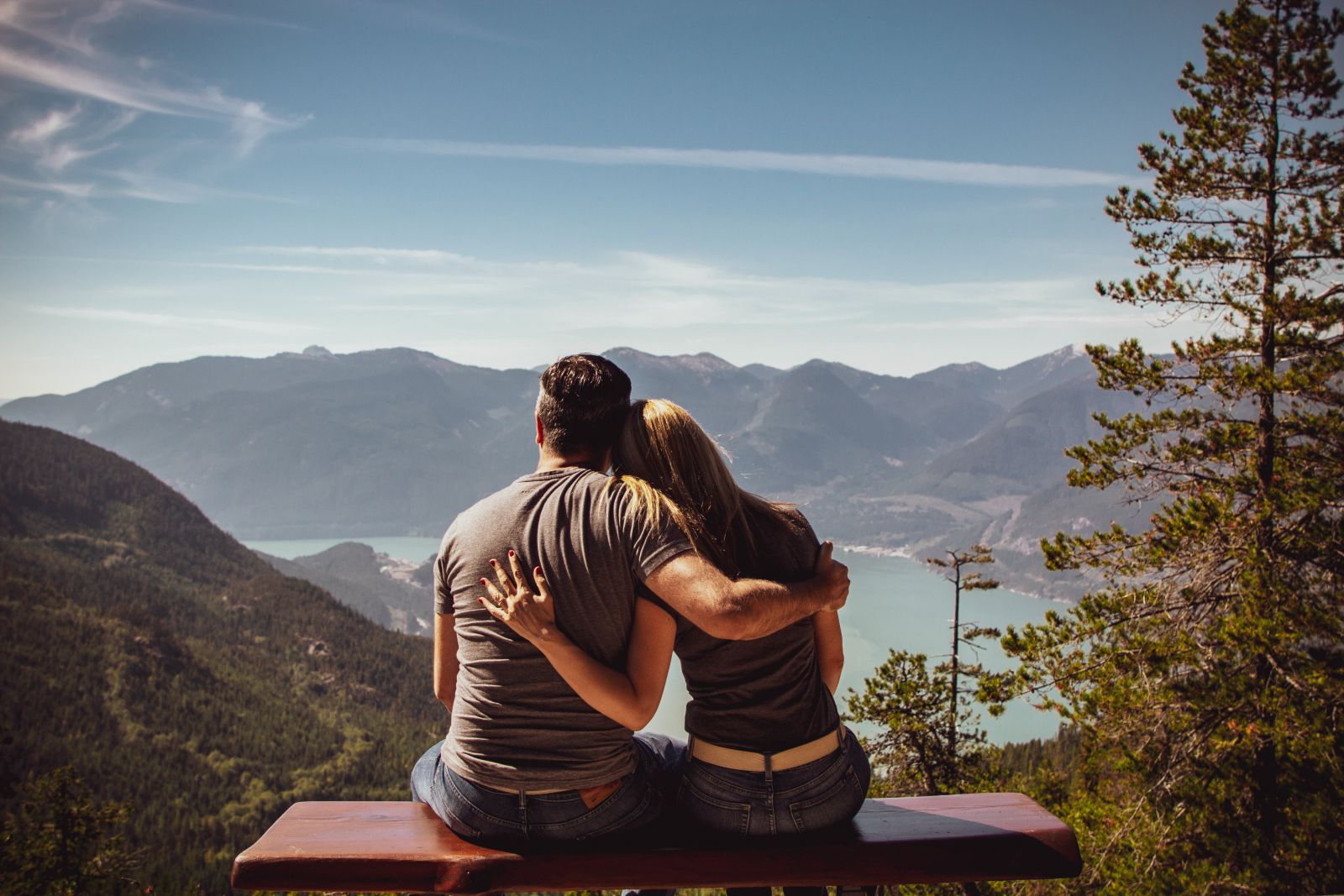 Casal de homem e mulher abraçados olhando para o horizonte com montanhas