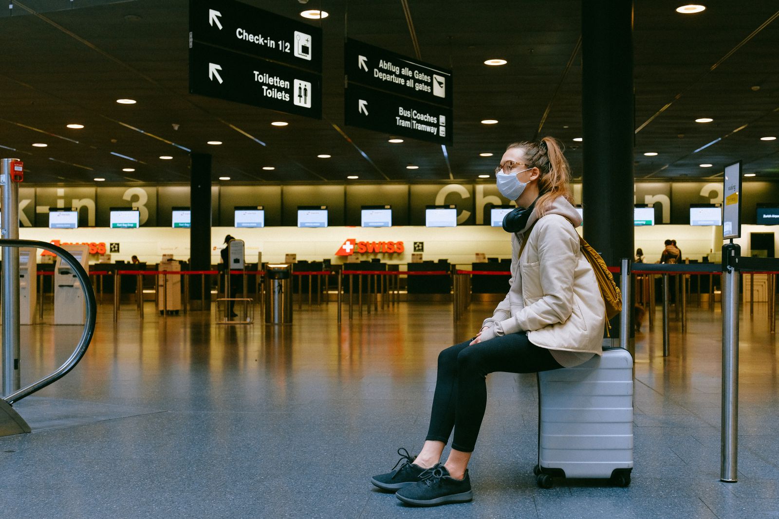 Mulher sentada na sua mala em um aeroporto