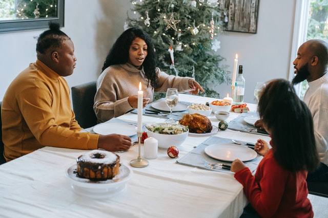 Família com dois homens e duas mulheres comendo e conversando durante ceia de Natal