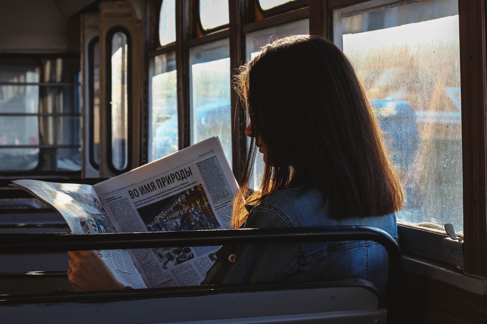 Mulher dentro de um ônibus lendo jornal