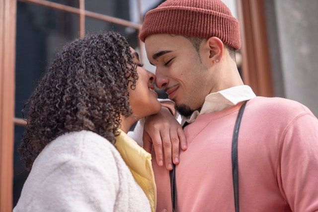 Mulher negra e homem branco se beijando.