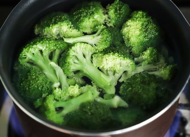 Brócolis sendo cozidos numa panela.