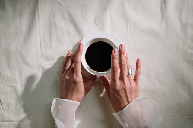 Mãos em cima de uma xícara de café