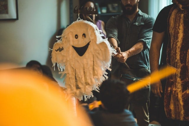 Piñata de fantasma com pessoas ao redor.