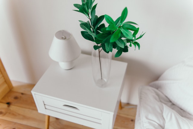 Mesa de cabeceira com abajur e um vaso de plantas