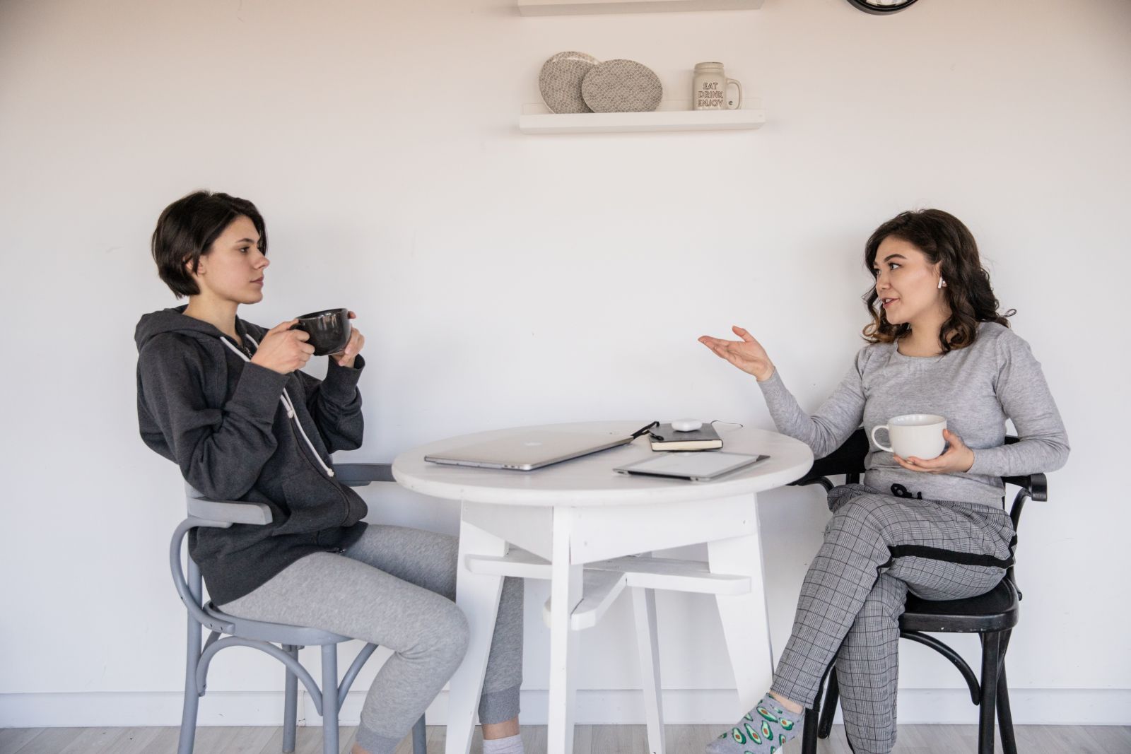 Duas mulheres segurando xícara de café e conversando