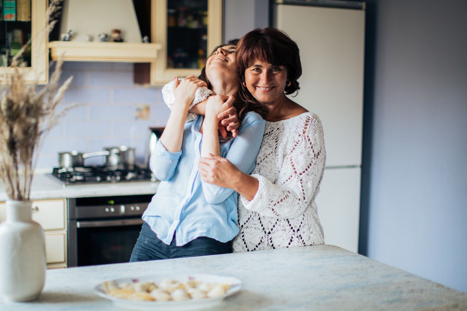 Mãe abraçando sua filha na cozinha
