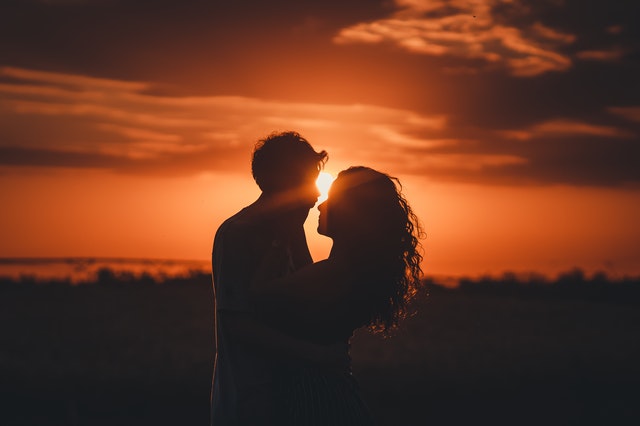 Silhueta de homem e mulher abraçados no pôr do sol.
