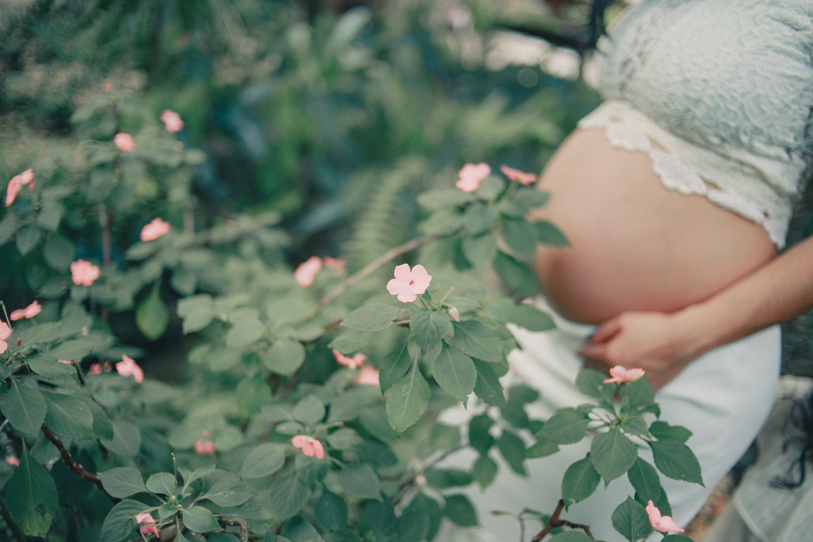 Mulher grávida ao lado de flores em um jardim