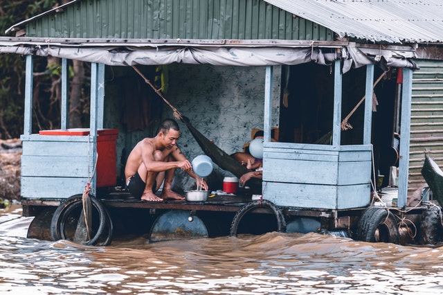 Pessoas ilhadas numa casa com enchente barrenta ao redor.