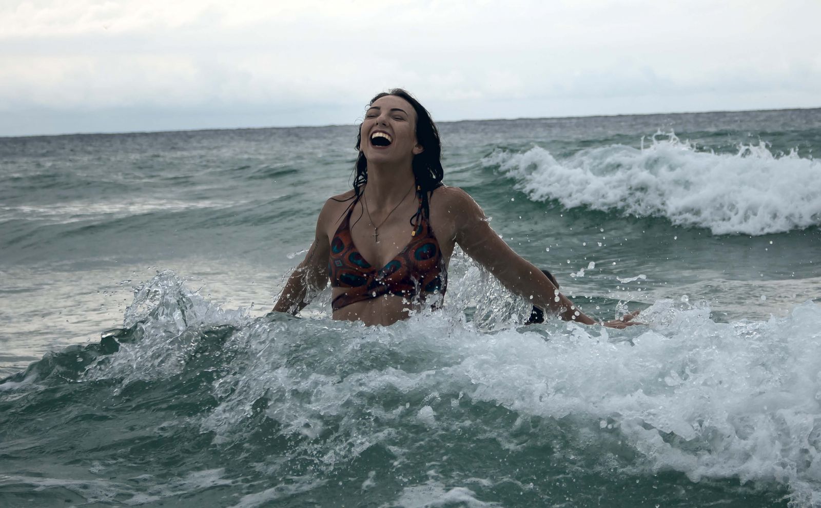 Mulher sorrindo no mar com ondas agitadas