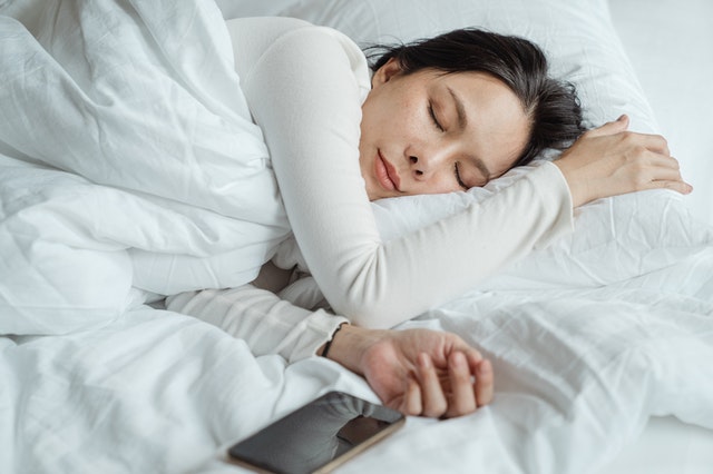 Mulher dormindo ao lado de um celular com um semblante calmo