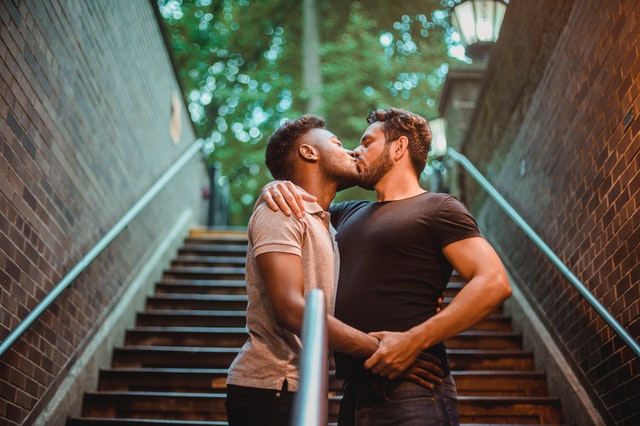 Homem branco e homem negro se beijando.