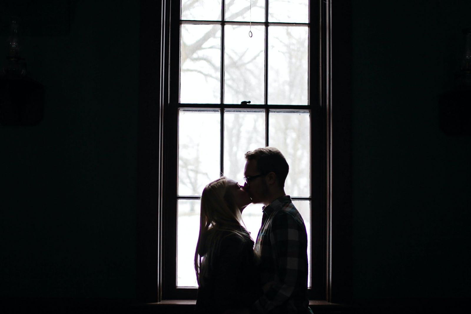 Casal se beijando ao lado da janela