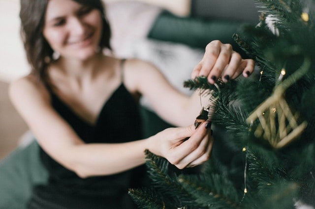 Mulher colocando um enfeite na árvore de Natal