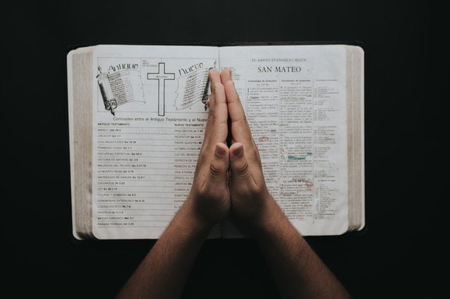 Pessoa com as mãos sobre uma Bíblia.