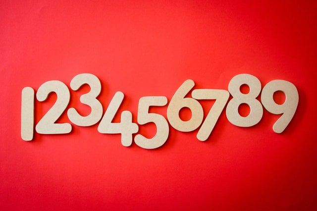 Números em madeira num fundo vermelho.