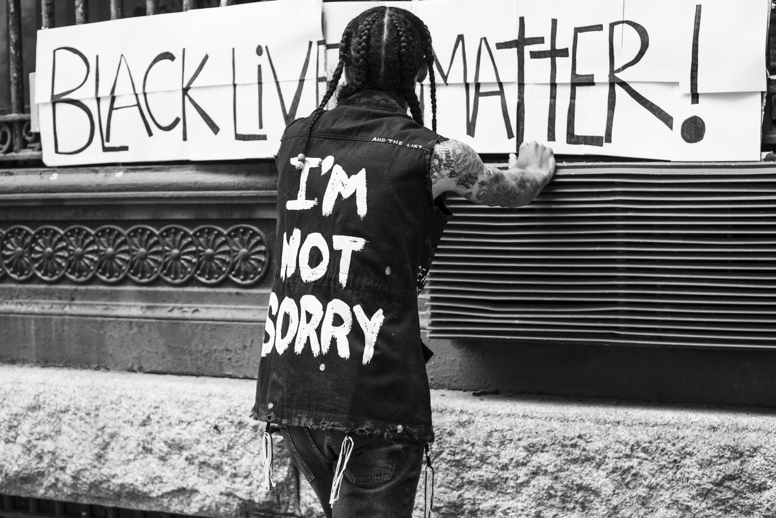 Pessoa de frente para um cartaz escrito Black lives Matter