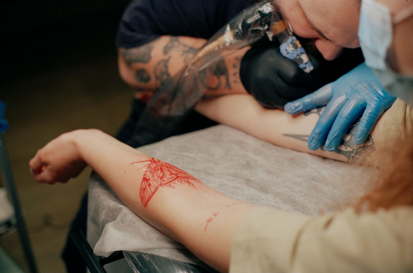 Tatuador fazendo tatuagem em uma mulher