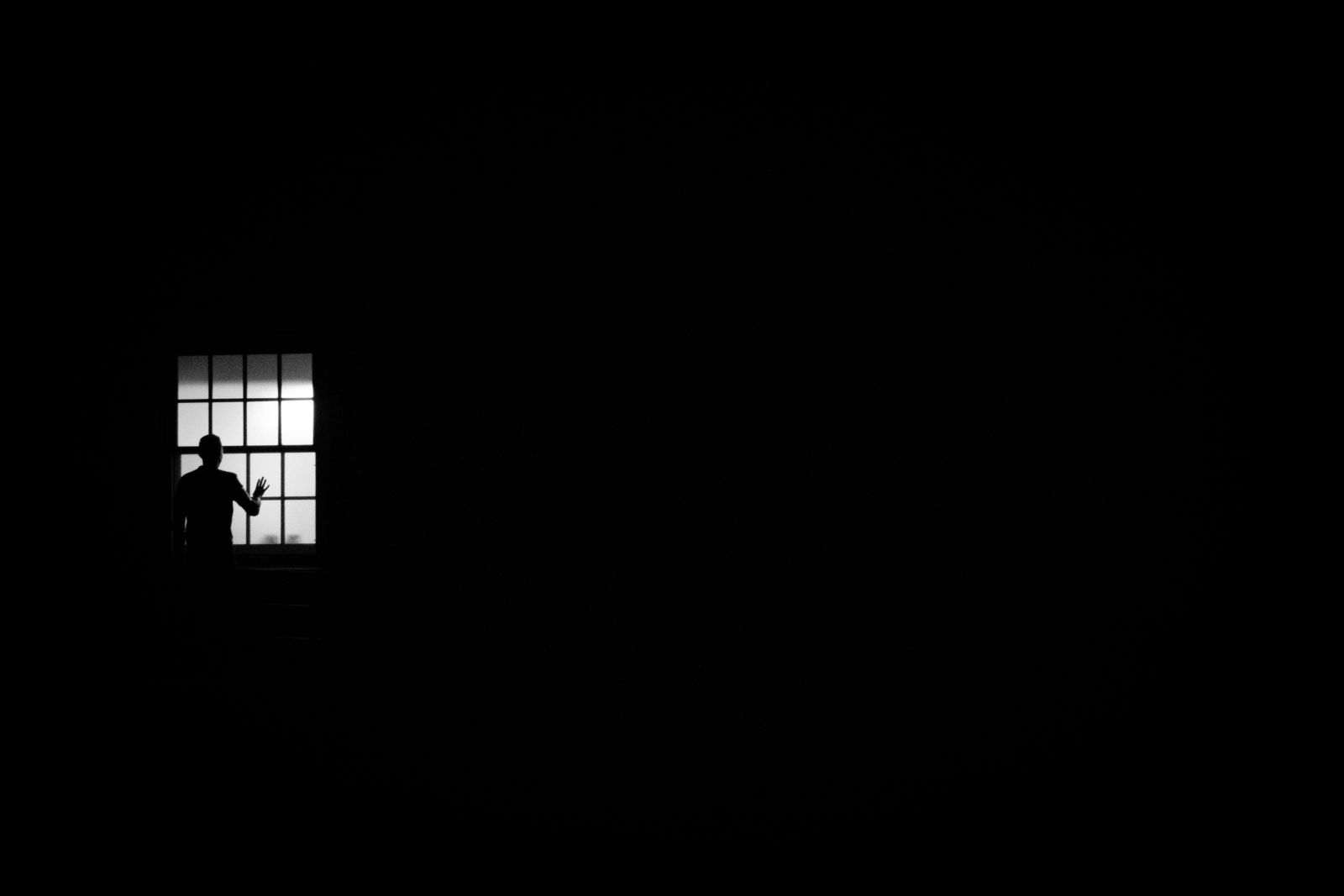 Homem na janela em um quarto escuro
