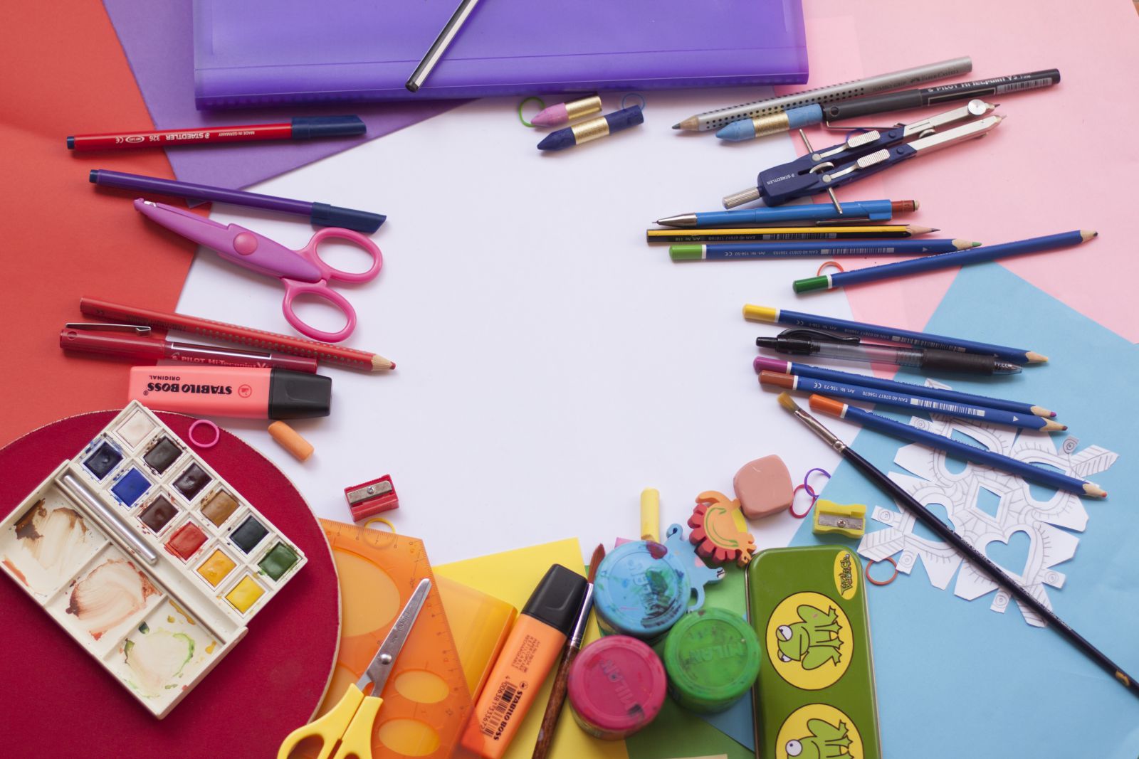 Mesa com lápis colorido, canetas, tintas e papéis 