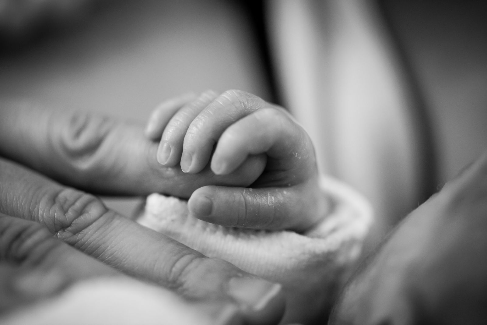 Bebê segurando mão de uma pessoa
