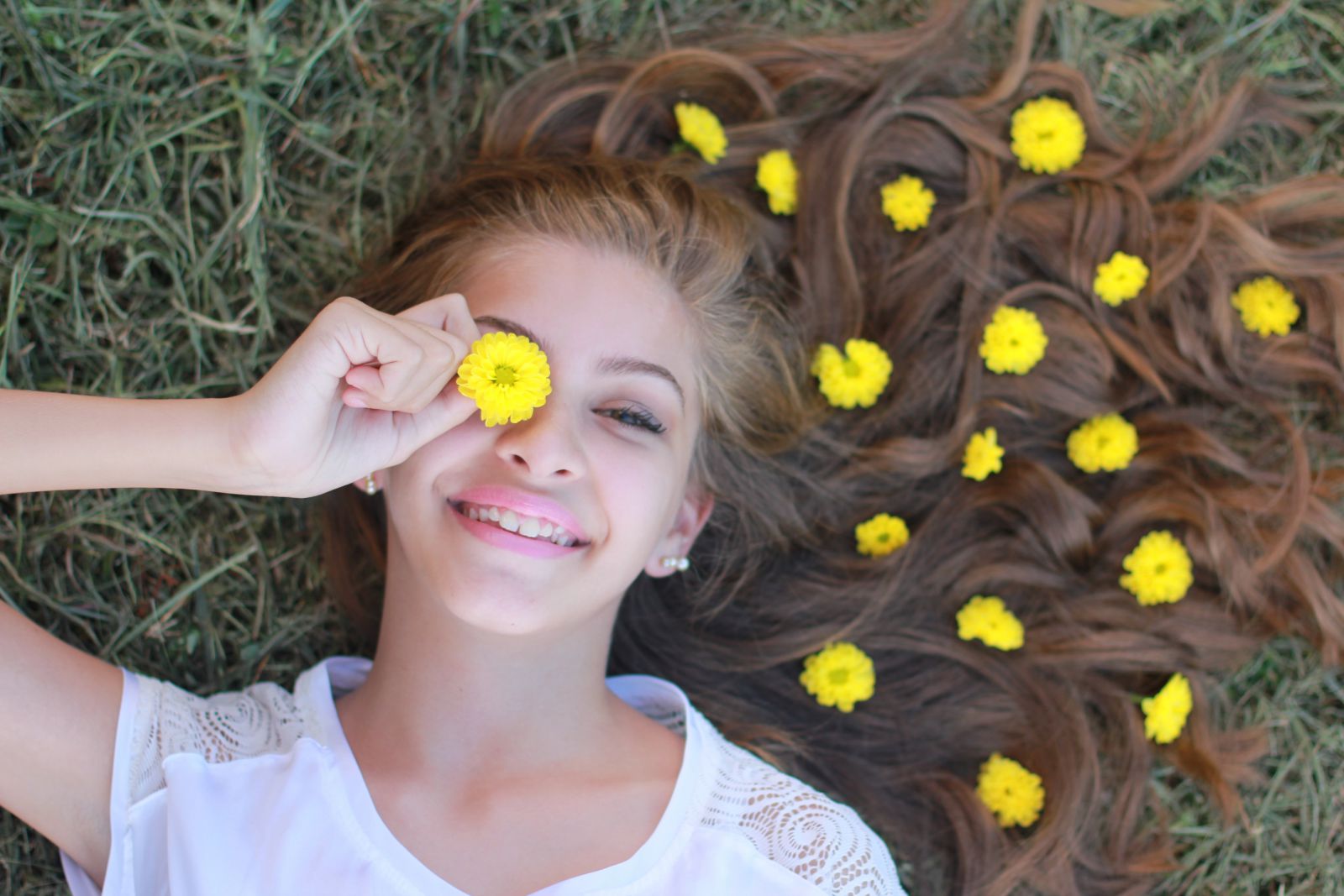 Menina branca loira deitada na grande com flores amarelas no cabelo.