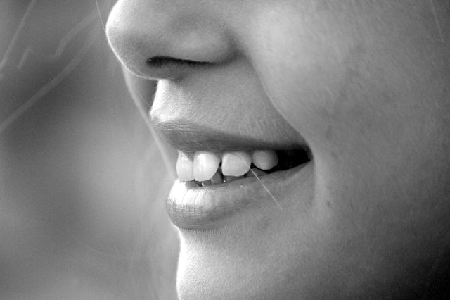 Mulher sorrindo e mostrando os dentes de perfil
