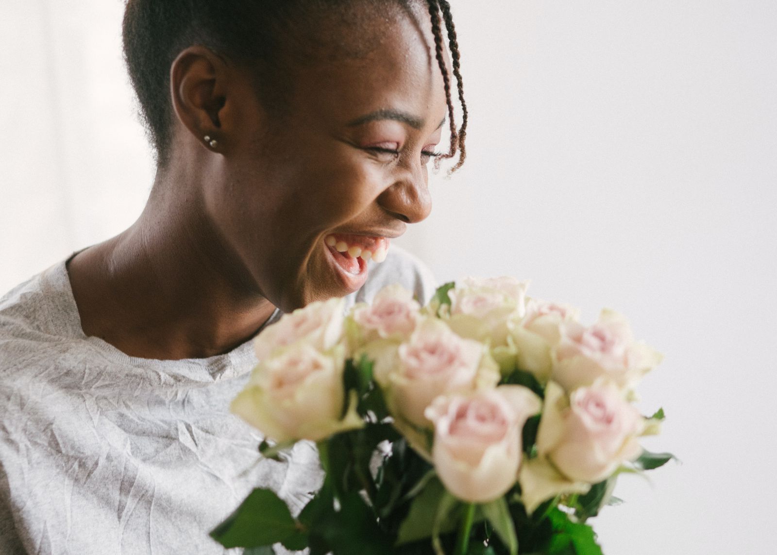 Mulher sorrindo em frente a um buquê de rosas