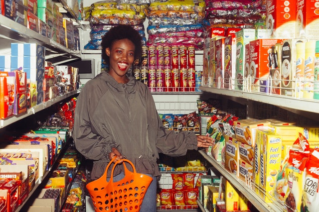 Mulher negra num supermercado com expressão sorridente.