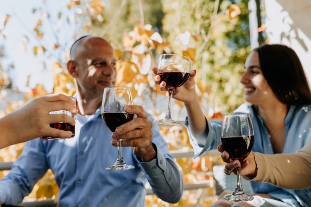 Homem e mulher sorrindo e brindando com taças de vinho na mão