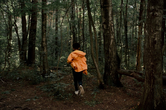 Menino negro correndo em floresta.