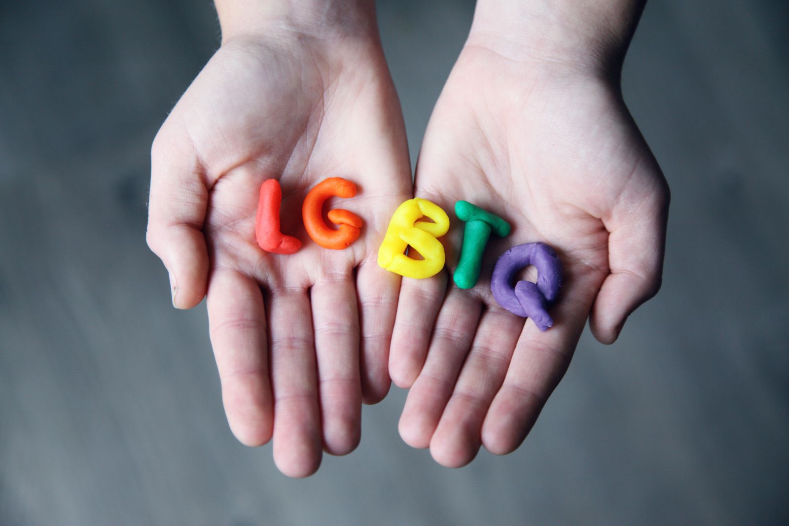 Pessoa segurando em suas mãos massinha com as letras LGBTQ