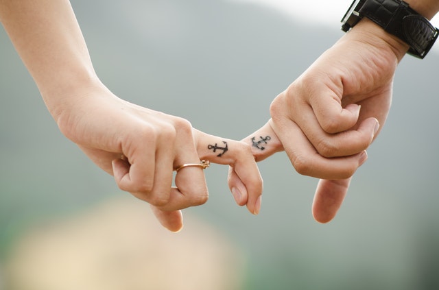 Mãos unidas com tatuagens de âncoras iguais