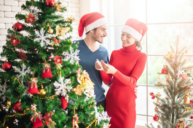 Casal sorrindo ao lado da árvore de Natal